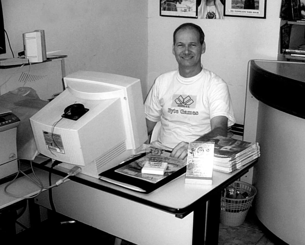 Petrúcio Prado sentado em sua mesa de trabalho na Byte Games, utilizando um computador 486 com processador x86, monitor CRT de tubo e sistema Windows 98 posteriormente atualizado para Windows XP. Foto histórica preservada pela TV Jampa Oficial e Folha do Valentina.