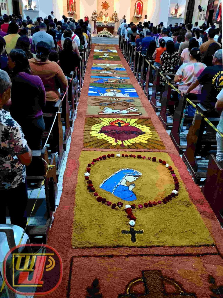 Detalhes do tradicional tapete de pó de serra colorido na igreja durante a celebração de Corpus Christi no Valentina Figueiredo com fiéis reunidos