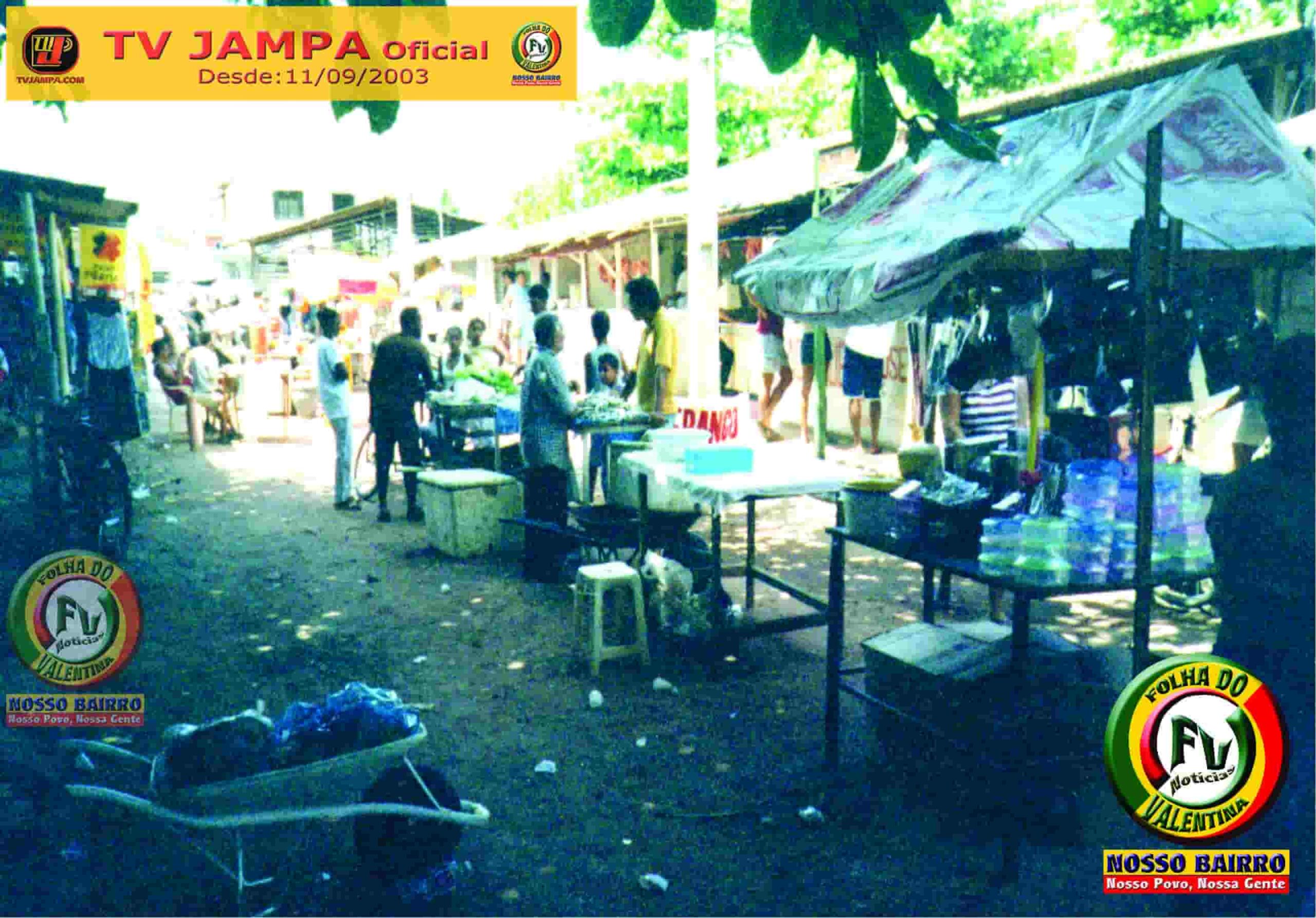 Fotografia antiga em preto e branco mostrando a movimentação de feirantes e clientes na feira livre do Mercado Público do Valentina em outubro de 2003.