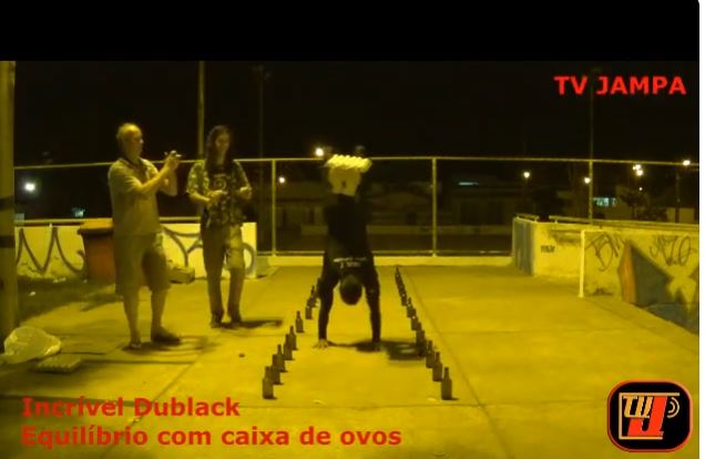 O atleta Incrível Dublack - Acorrentado aos pés equilibrando com caixa de ovos com patrocínio da TV Jampa Oficial Prado.
