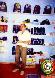 Comerciante Josias Henrique Xavier em pé em frente às prateleiras de sapatos da loja Magazine Xavier Calçados no Mercado Público do Valentina em outubro de 2003.