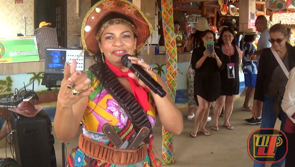Cantora Ana Virgínia caracterizada de Maria Bonita com microfone e peixeira cantando no Pavilhão do Forró do Shopping Rural de Conde, Paraíba, em cobertura da TV JAMPA Oficial.