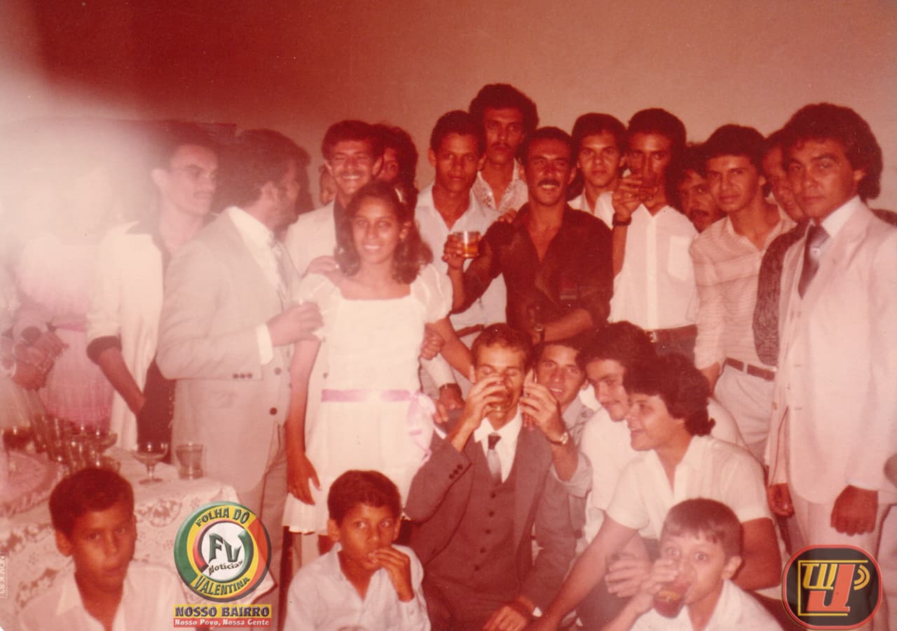 Fotografia antiga com tom amarelado e efeito envelhecido, registrando uma comemoração de casamento lotada em 8 de outubro de 1983 de Petrúcio Prado TV Jampa Oficial e sua esposa Rejane Prado. No centro, uma jovem noiva sorri de vestido branco com faixa rosa na cintura. Atrás dela e ao redor, um grande grupo de homens com trajes sociais da época posa sorrindo. Um homem de terno cinza e gravata, sentado à frente, bebe em um copo. No canto inferior esquerdo, duas crianças aparecem em primeiro plano perto de uma mesa com taças. A imagem traz os logotipos "Folha do Bairro Notícias - Valentina" à esquerda e "TV Jampa" à direita.