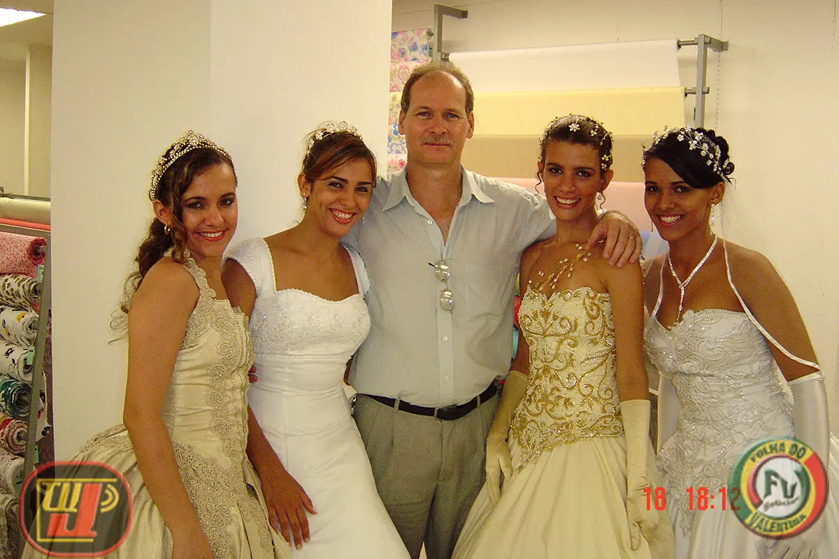 Fotografia colorida em plano médio mostrando o diretor Rafael Prado vestindo camisa social clara no centro, acompanhado por quatro modelos sorridentes vestidas com trajes de noiva detalhados, tiaras e arranjos nos cabelos. Da esquerda para a direita, a imagem apresenta Alessandra, Ada, Petrúcio Prado, Cintia e Leidy Anny. No canto inferior esquerdo está o logotipo da TV Jampa e no canto inferior direito a marca da Folha do Valentina com a data impressa em vermelho "18 18:12".