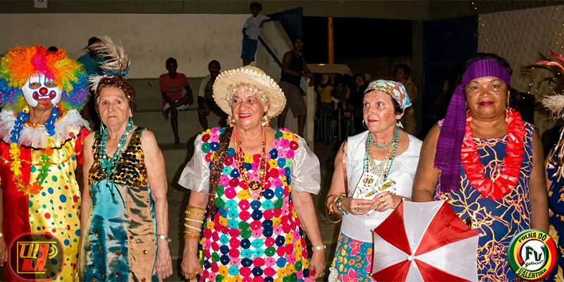 Baile Carnaval dos Idosos com participantes fantasiadas de palhaço e baiana