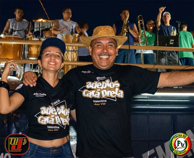 Coordenador João Cunha e sua esposa sorrindo juntos no desfile do Bloco Adeptos da Cara Preta em 2006.