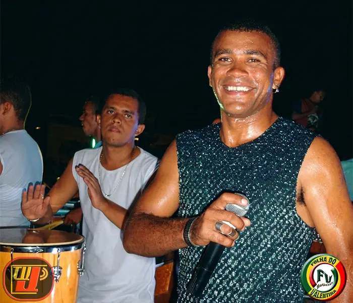 Vocalista Marcone cantando com microfone em cima do trio elétrico no desfile do Bloco Adeptos da Cara Preta.