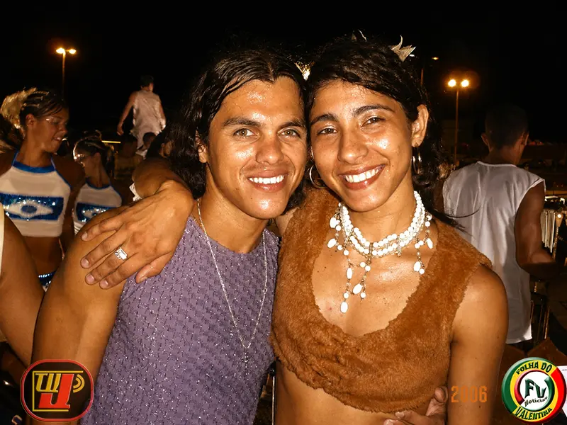 Vocalistas Ebison e Fernanda Felix sorrindo juntos durante o desfile do Bloco Adeptos da Cara Preta.