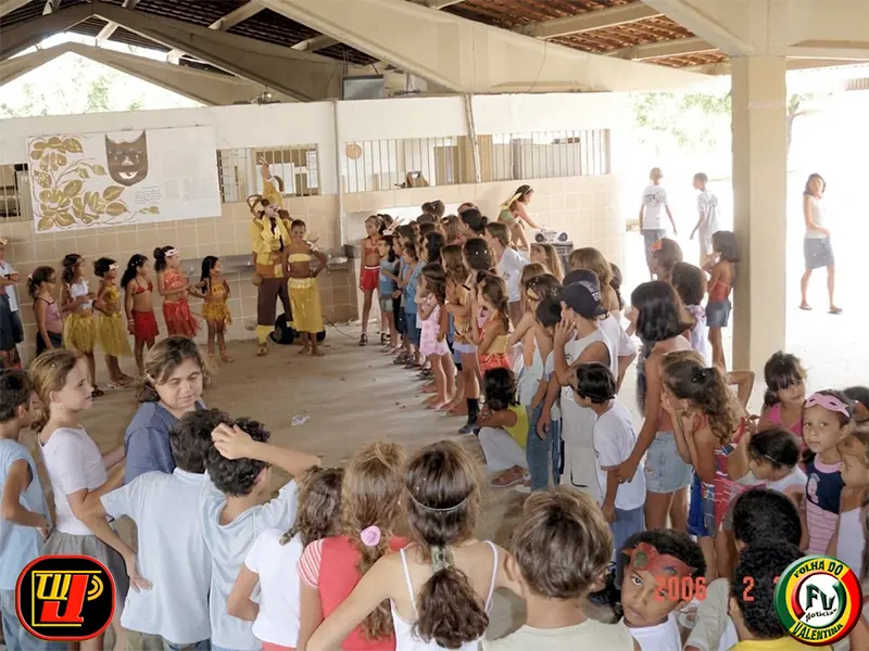 Crianças reunidas em círculo assistindo a uma apresentação cultural em área coberta durante o Carnaval Beneficente Dr. João Navarro.