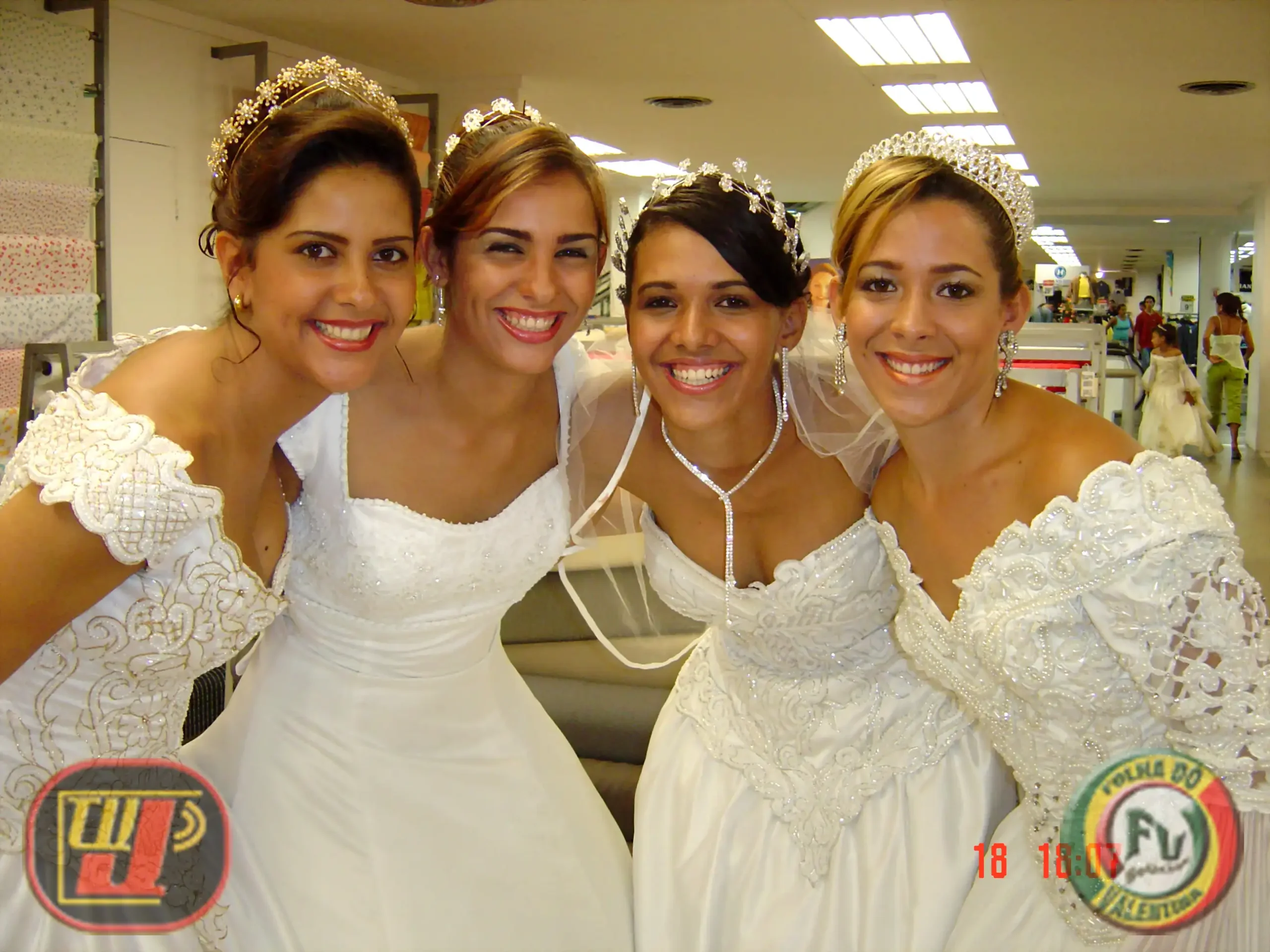 Expor Noivas Esplanadas fotografia colorida em plano médio de quatro mulheres sorridentes reunidas lado a lado nos bastidores de um evento dentro de uma loja. Todas vestem elegantes vestidos de noiva brancos com bordados detalhados, usam tiaras brilhantes nos cabelos e brincos delicados. Da esquerda para a direita, a imagem mostra Carol, Ada, Leidy Anny (com véu de noiva e colar longo) e Mary Anne. No canto inferior esquerdo está o logotipo da TV Jampa e no canto inferior direito a marca da Folha do Valentina com a data impressa em vermelho "18 18:07".