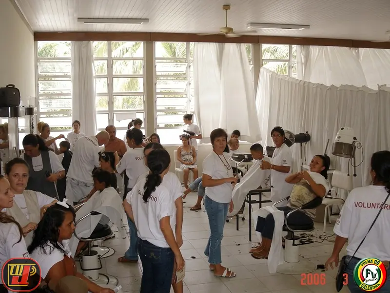 Voluntários realizam cortes de cabelo e serviços de beleza em várias pessoas dentro de um salão estruturado durante o IV Dia Nacional de Ação Voluntária Fundação Bradesco.