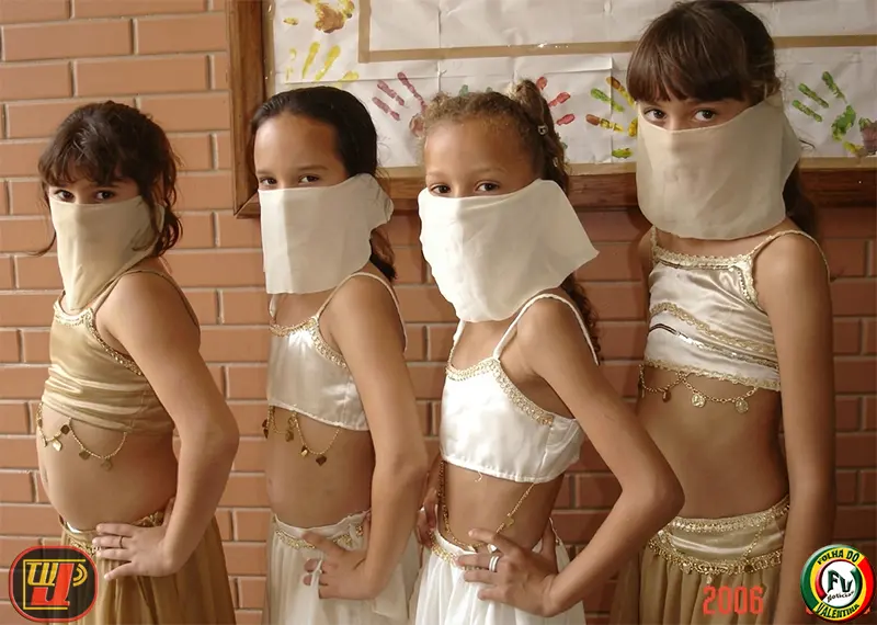 Quatro crianças vestidas com trajes de dança do ventre e lenços cobrindo o rosto posam juntas de perfil durante o IV Dia Nacional de Ação Voluntária Fundação Bradesco.