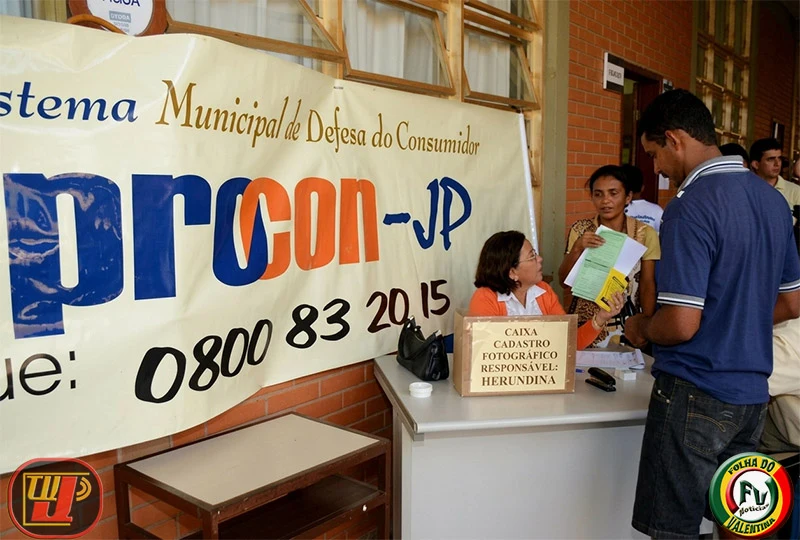 Balcão de atendimento do Procon-JP com uma grande faixa do Sistema Municipal de Defesa do Consumidor ao fundo durante a ação voluntária na Fundação Bradesco.