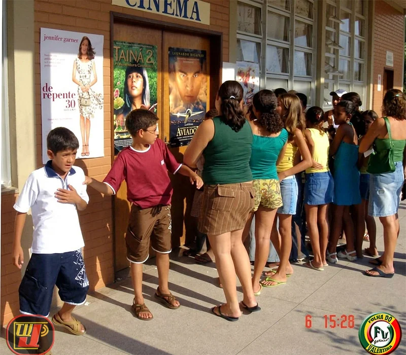 Crianças, jovens e adultos organizados em fila na entrada da sala de cinema durante a ação voluntária na Fundação Bradesco.