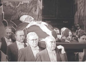 Corpo do Papa João Paulo II em vestes litúrgicas vermelhas sendo carregado em cortejo fúnebre por dignitários e carregadores no Vaticano em abril de 2005.