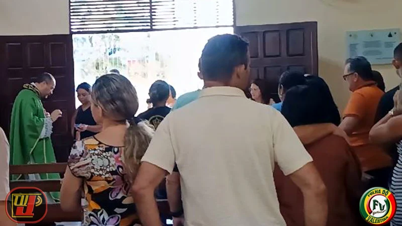 Fiéis acompanham a missa dentro da igreja enquanto o Padre Luiz Carlos, vestindo casula verde, abençoa utensílio de fiéis.