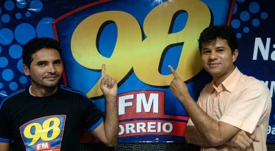 Anderson Soares e Roberto Targino em frente ao painel da 98 FM Correio